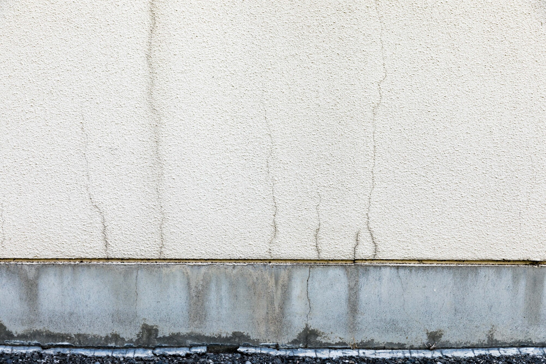 モルタル外壁に縦に伸びる多数のクラック