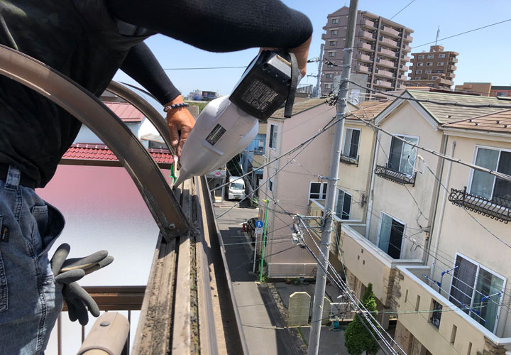 職人さんが掃除機とワイヤーブラシで清掃するテラス屋根のフレーム