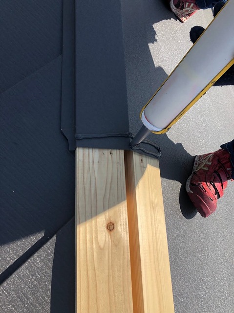 棟板金にコーキングをしている様子