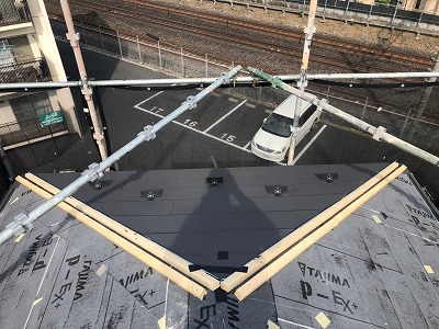 屋根材を取り付けている写真です。棟の部分には下地の木材を取り付けます。