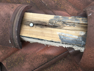 棟瓦が外れて貫板がむき出しになっている