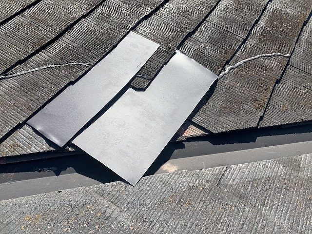 穴の開いた屋根に板金を差し込んで応急処置