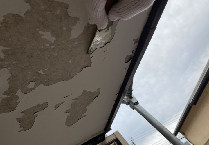 皮スキで既存の塗膜を剥がす様子