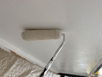 ローラーで軒天の塗装をしている様子