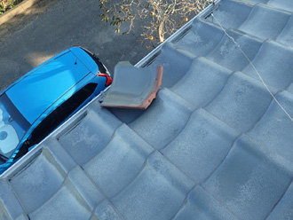 外れた瓦が屋根から落ちそうになっている