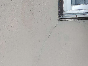 2階の窓サッシから差し掛け屋根に向かって伸びる外壁クラック