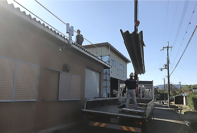 新しい折板屋根をクレーンで持ち上げ倉庫の屋根の上に乗せます