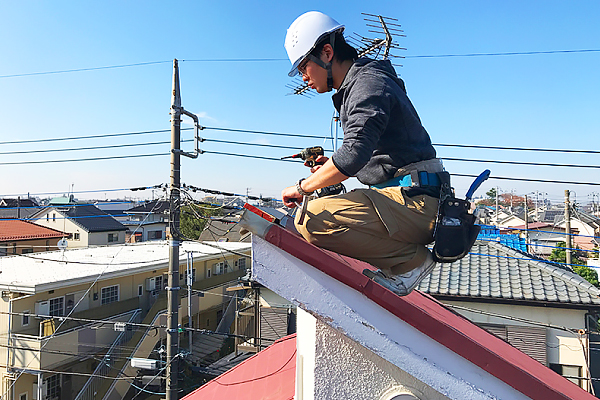 片流れ屋根の上で修理を行うプロの業者