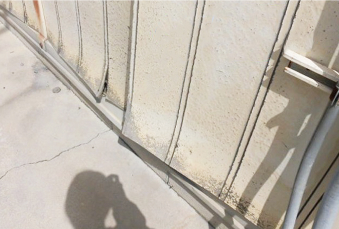 プレハブの外壁材の下部が沿って変形しています