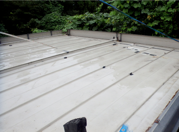 雨漏りを引き起こし、防水テープで所々応急処置が施されたプレハブの屋根